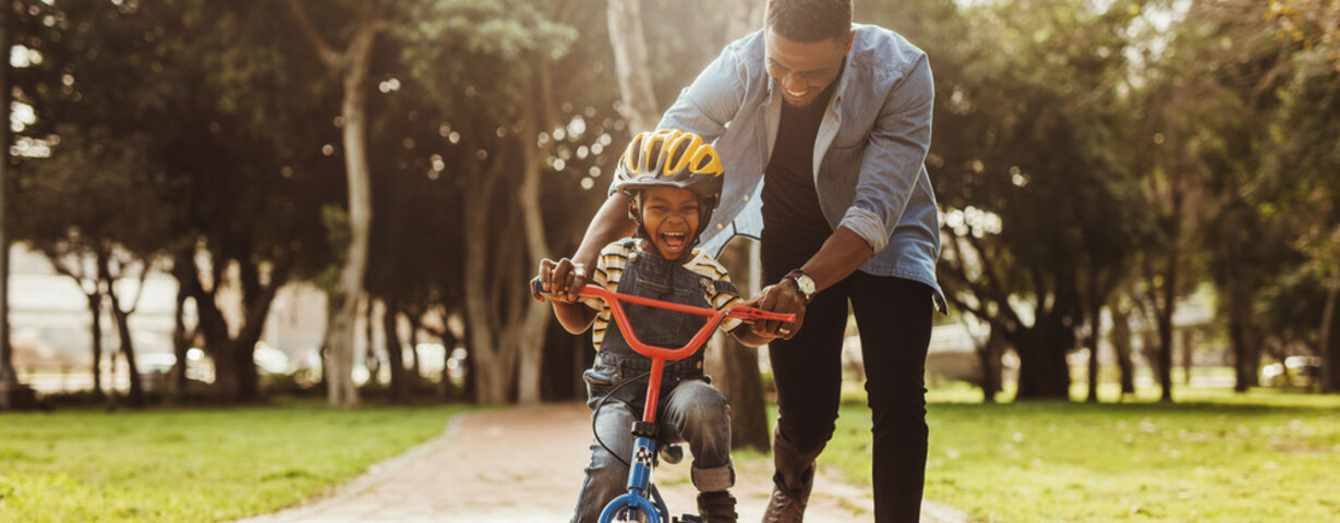 Padre enseñando a su hijo a andar en bicicleta en el parque